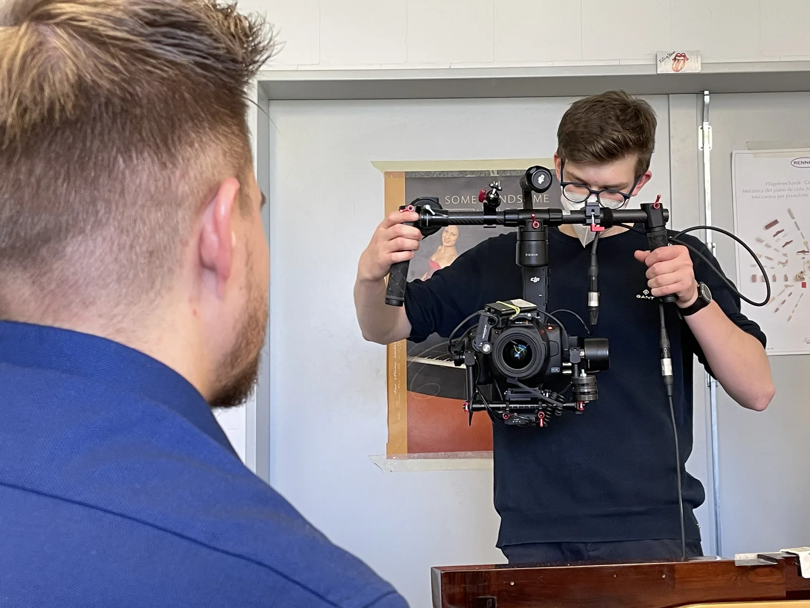 Constantin filmt mit einer Kamera auf einem Gimbal in der Blüthner-Werkstatt.
