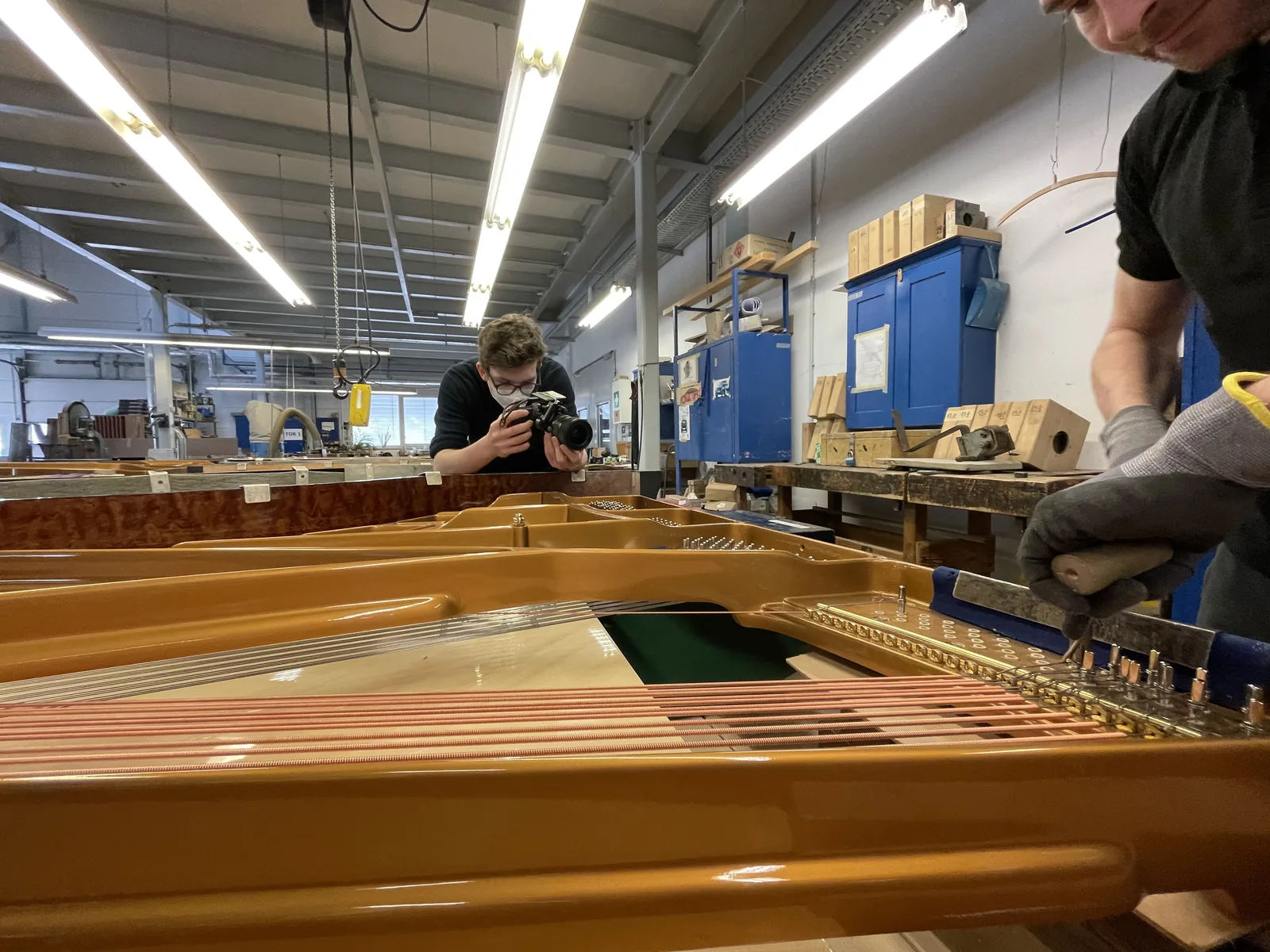 Kameraaufnahme von Handarbeit an den Saiten eines geöffneten Flügels.