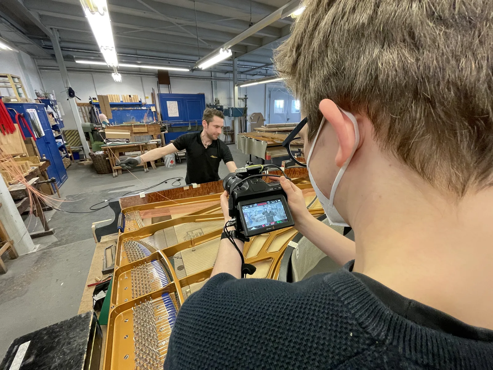 Blick über eine Kamera auf die Arbeit an einem Flügel.