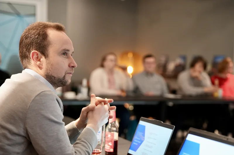 Teilnehmende bei einer Veranstaltung mit Laptops an einem Tisch.