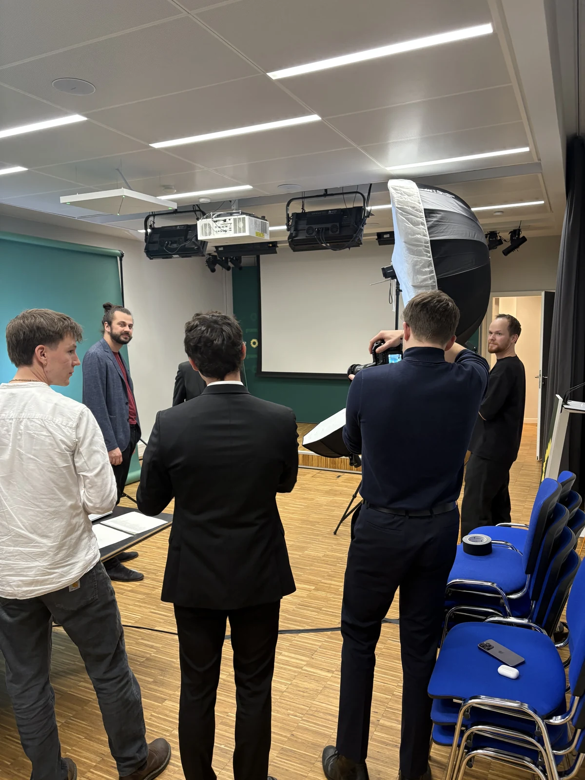 Ein Fototeam bereitet eine Gruppenaufnahme vor einer grünen Hintergrundrolle vor.