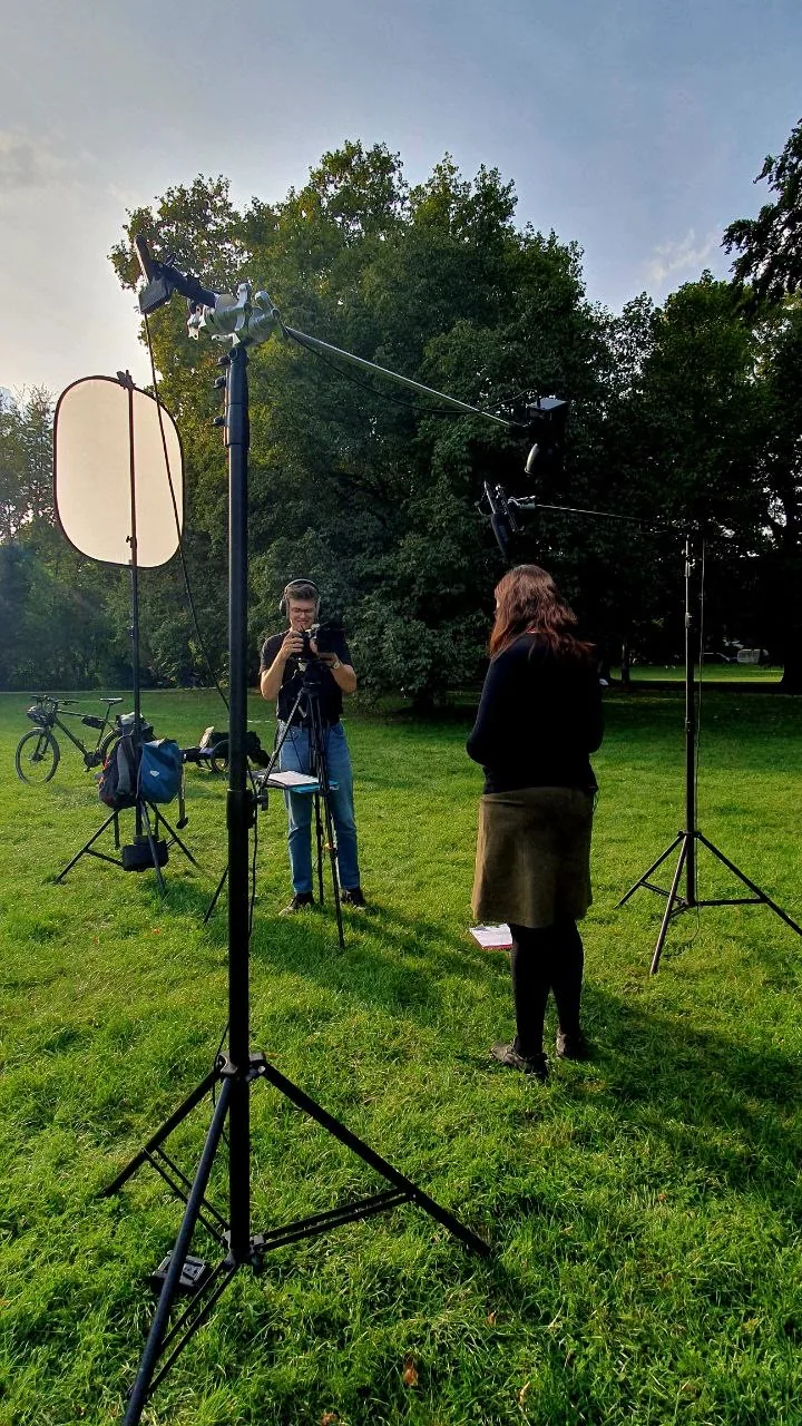 Aufnahmeaufbau mit Kamera, Mikrofonangel und Reflektor auf einer Wiese.