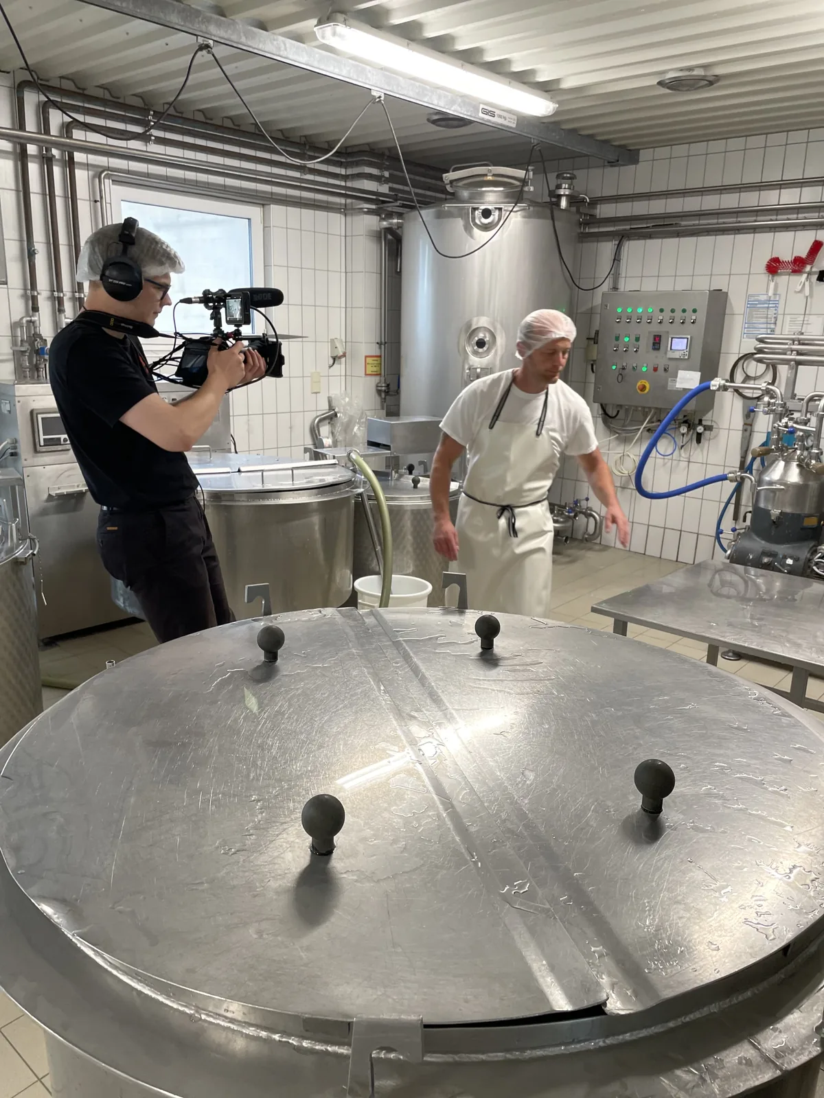 Kameraaufnahme zwischen großen Edelstahlbehältern in der Produktion.