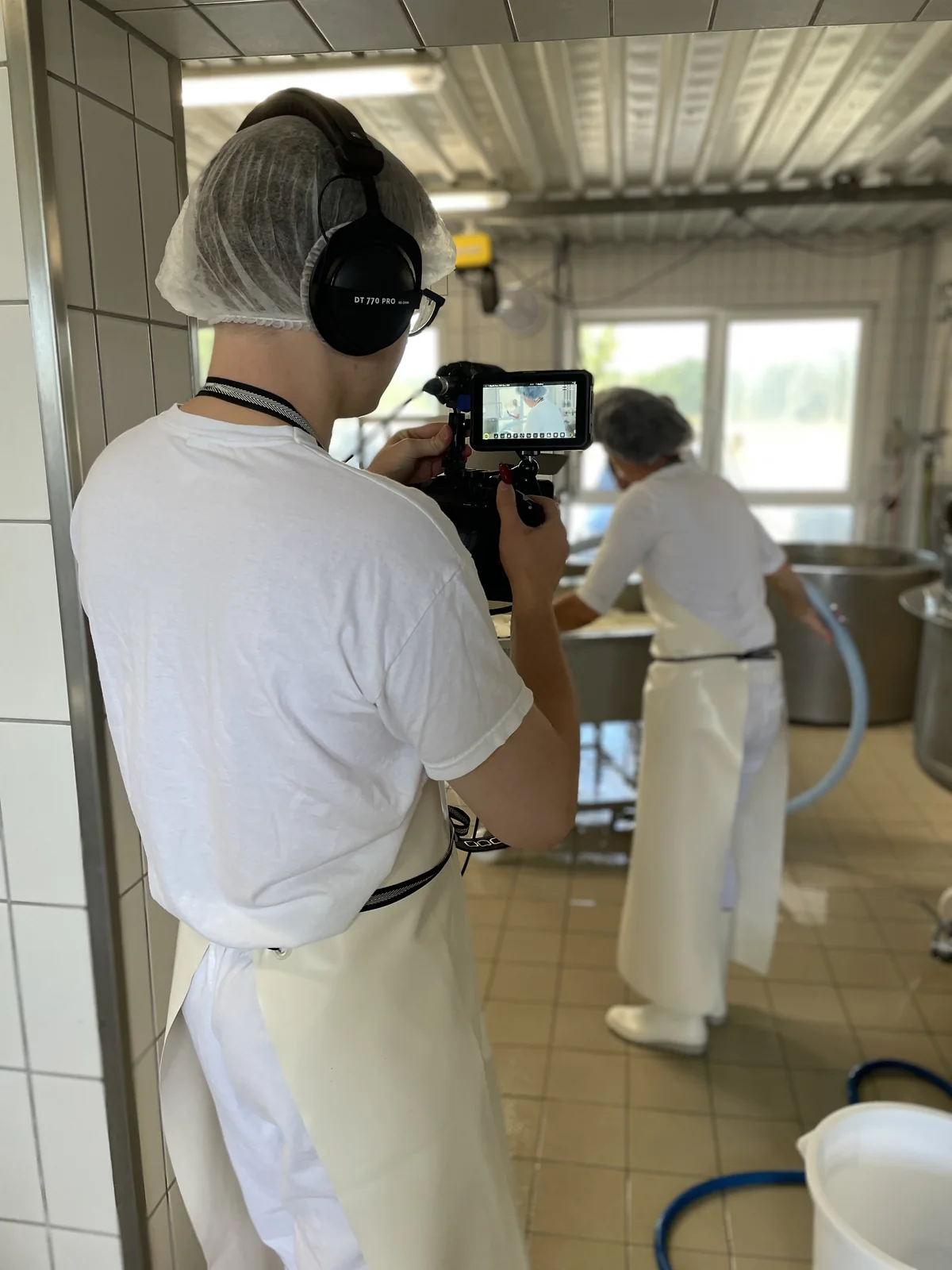 Blick über die Schulter des Kameramanns auf eine Mitarbeiterin bei der Produktion.