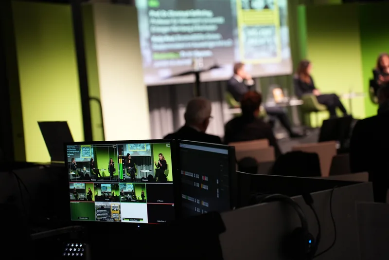 Bildschirme einer Multicam-Regie während einer Podiumsdiskussion.