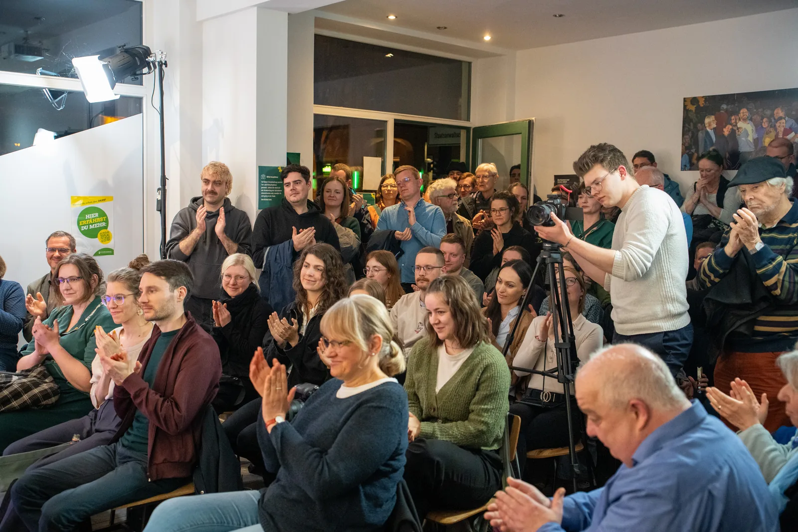 Kameraaufnahme mitten im Publikum mit einer großen Lichtanlage im Hintergrund.