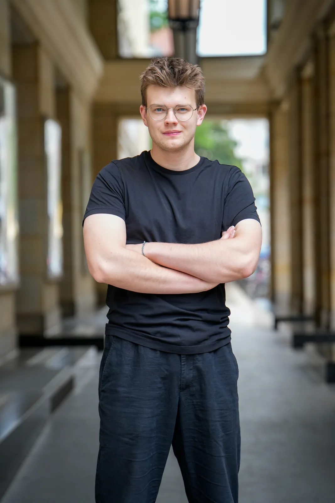 Constantin von rohninifilm mit verschränkten Armen zwischen Säulen.