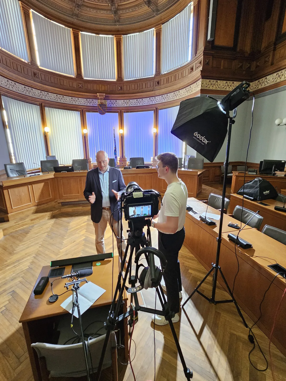 Blick hinter eine Kamera während eines Interviews im Saal.