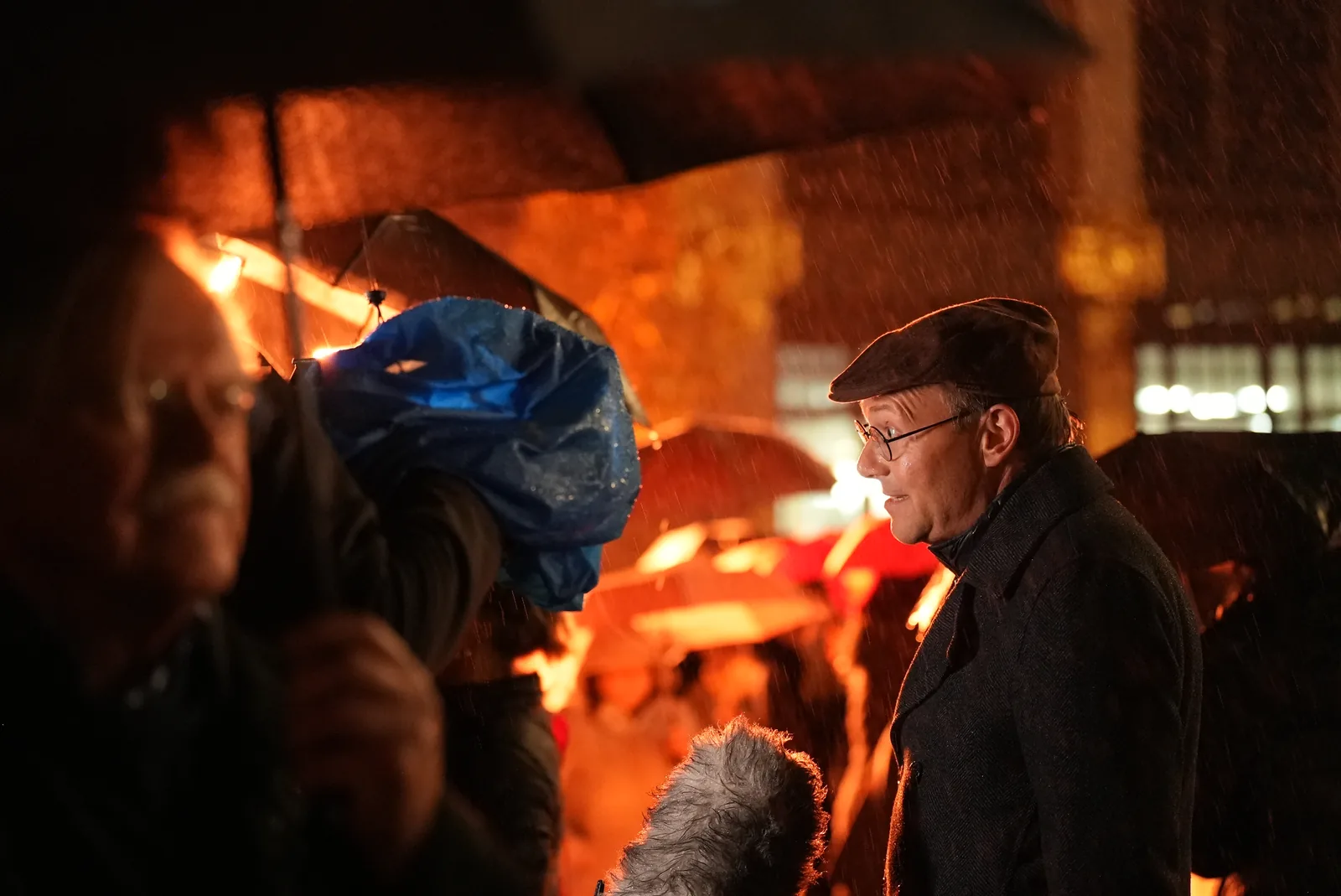 Wolfram Günther bei einer Gesprächsaufnahme im Regen vor orangefarbenem Licht.